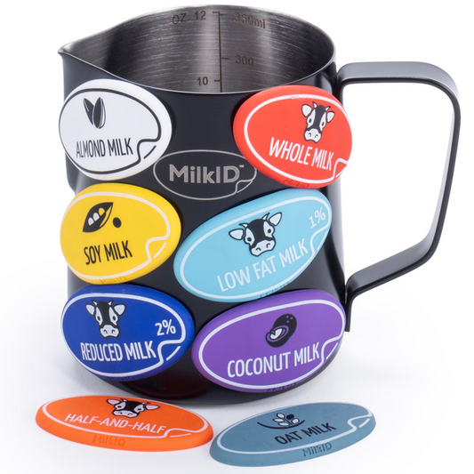 Black stainless steel pitcher with color-coded snap-on labels for identifying various milk types, including whole milk, oat milk, and soy milk.